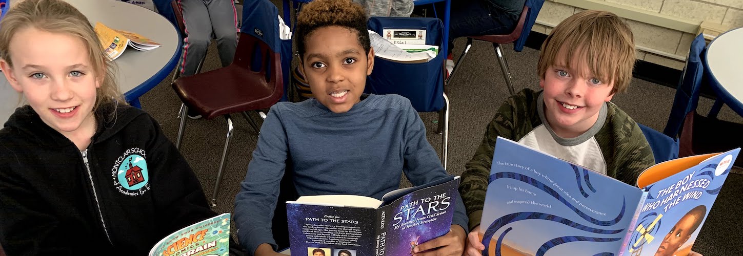 Three students posing with books