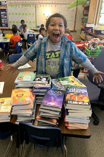 Student posing with a stack of books