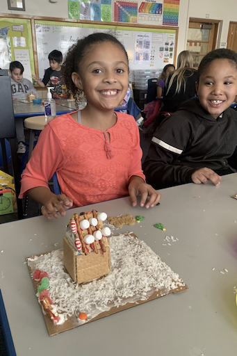 Student posing with a ginger bread house